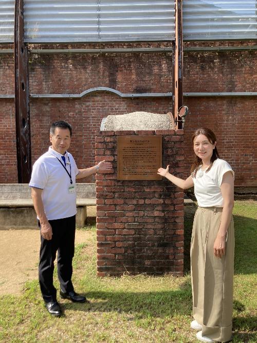 レンガ館ボイラーベンチの前で記念撮影する藤原町長と井上リポーター