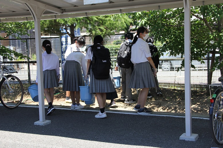 駐輪場付近のゴミを拾う生徒たちの写真