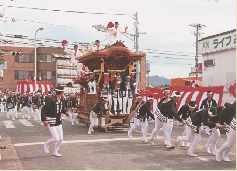 一列でひもを交互でもち久保地車を引いている写真