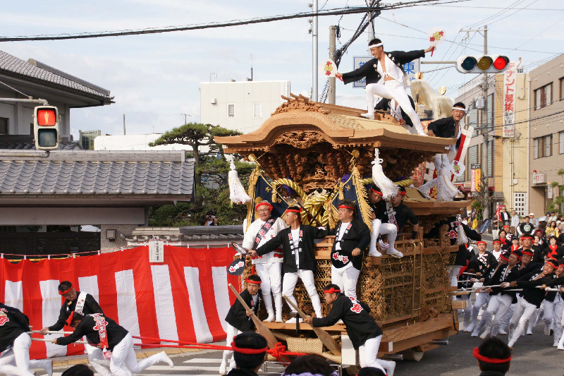 信号を曲がったばかりの大宮地車を赤いねじり鉢巻き姿の関係者が引いている写真