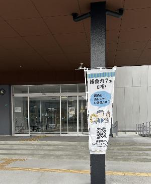 かむかむプラザの玄関にのぼりを立てています 議会カフェオープンの目印です