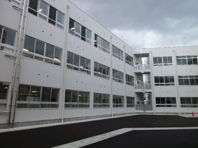 3階建てで白壁の西校舎の写真