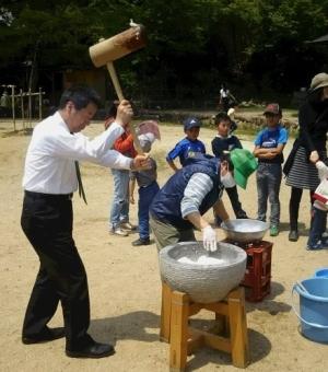 杵を振りあげ餅つきをする町長の写真