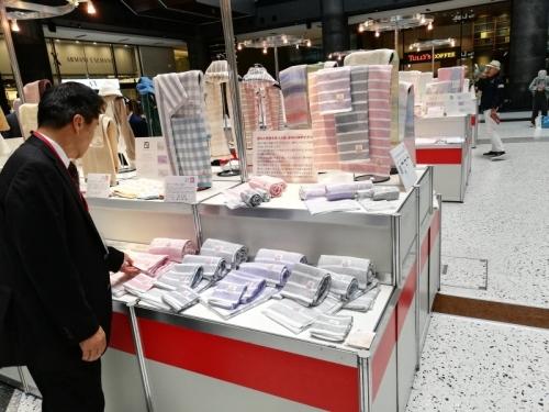 台の上にボーダー柄やチェック柄のタオルが沢山置かれていて、町長がタオルを触っている写真