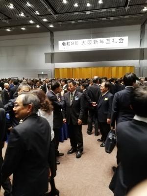 中央にはスーツ姿の男性と話をしている町長、周りにもスーツ姿の人たちが沢山集まって立ち話をしている写真