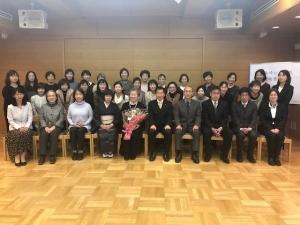 緑綬褒章を受章された森崎シヅ子さんと、お祝いの会の参加者が3列に並んでいる集合写真