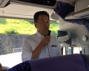 バスの中で、マイクをもって話をしている町長の写真