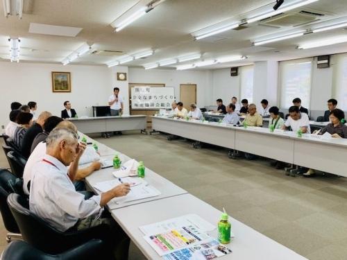マイクを持ち前に立って話す町長と、資料を見ながら話を聞く参加者の写真