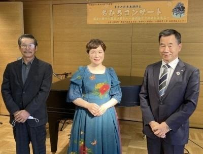 中央に青いワンピース姿のちひろさん、右側に町長、左側にスーツ姿の男性が横並びに並んでいる記念写真