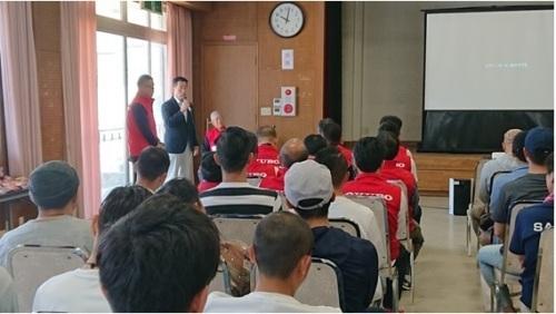 スクリーンの横でマイクを持ち前で話す町長と座って聞く参加者を後方から写した写真