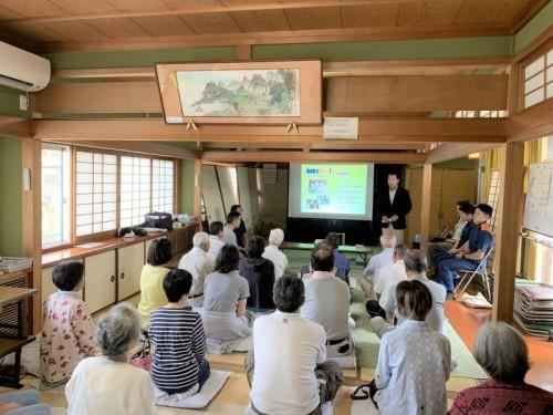 スクリーンの横で話す町長とそれを参加者が聞いている写真