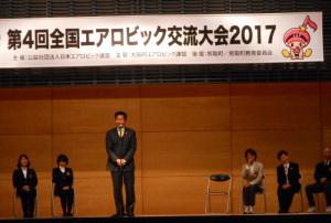 エアロビック交流大会で、舞台のマイクの前に立っている町長の写真