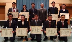 賞状を持った9名の男女と、町長と、男性が2列に横に並んでいる記念写真