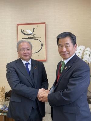 町長と山口副知事が横並びでお互いの両手を重ねて握手をしている写真
