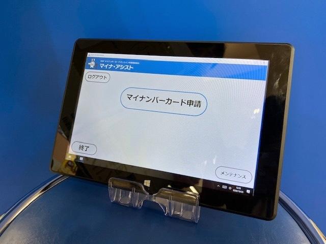 マイナンバーカード申請と画面に表示されている「マイナ・アシスト」のタブレット端末の写真