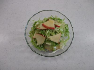 透明の器にキャベツとリンゴを和えたサラダが盛りつけられた写真