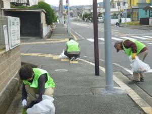 緑色の蛍光チョッキを着たアドプトロード「希望が丘」の人達が歩道のごみ拾いを行っている写真