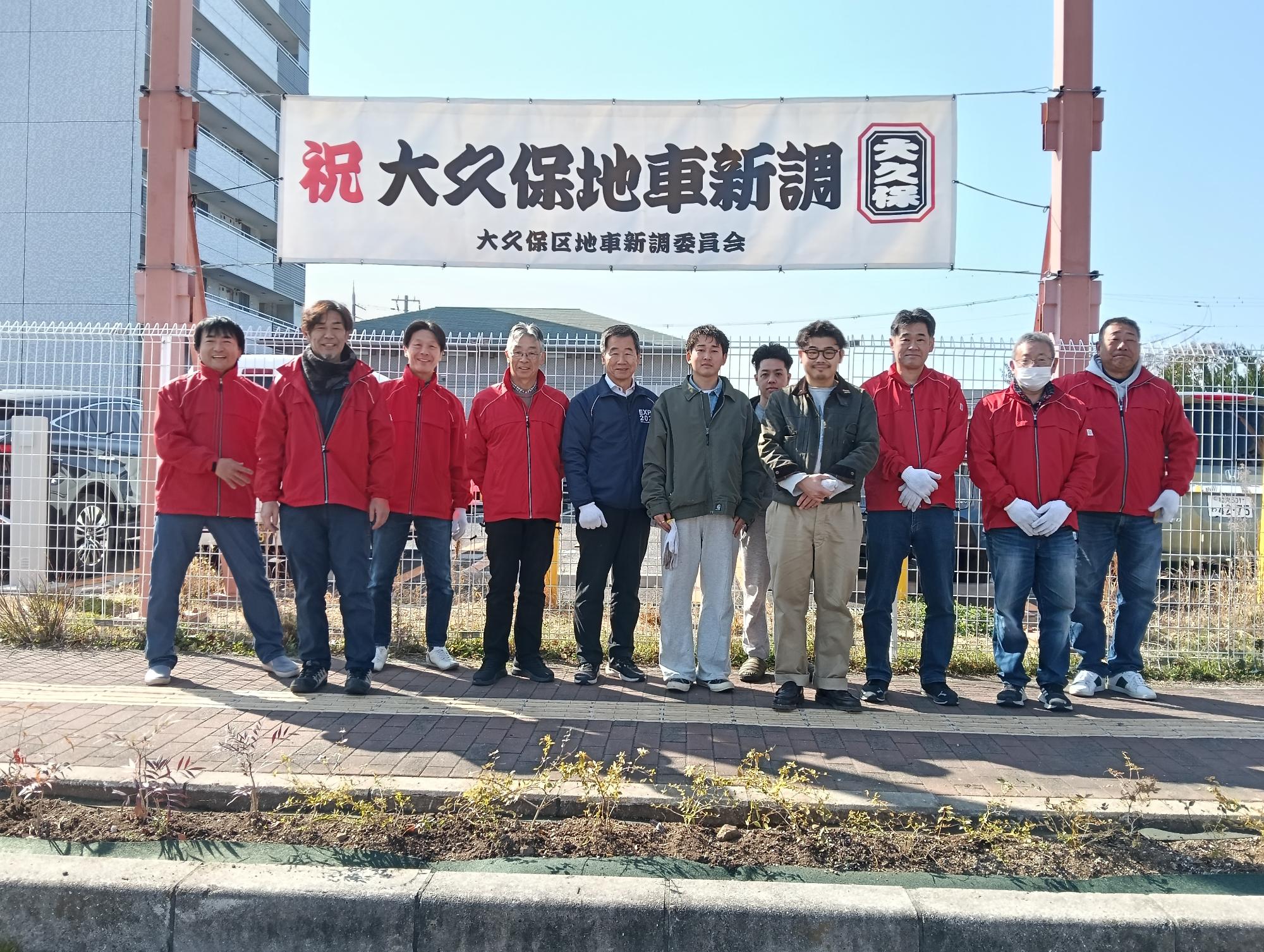大久保区が熊取駅前線植樹帯で記念撮影をしている写真