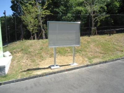 公園内の通路の脇に設置された、入口横の掲示板の写真