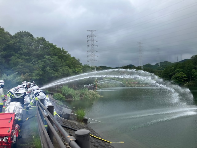 池に向かって放水する消防団員の写真（横から）