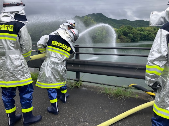 池に向かって放水する消防団員の写真（後ろから）