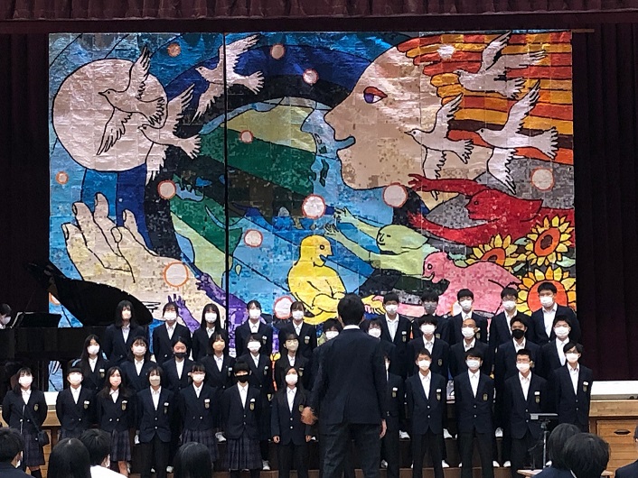 ビッグアートの前で合唱する生徒たちの写真