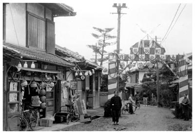 紅白で飾られた熊取町町制実施記念と記載された門と行きかう五門地区の人々の白黒写真