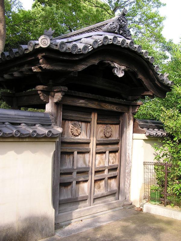 瓦で造られた屋根と木で造られた扉がついた門が大きく写っている写真