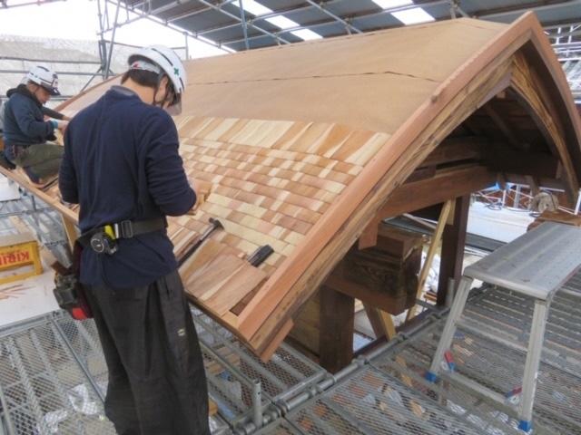 表門の屋根に薄い板を葺いている様子の写真