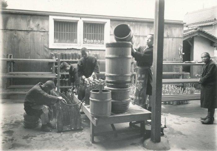 樽から酒を瓶詰作業をしている5人の男性の白黒写真