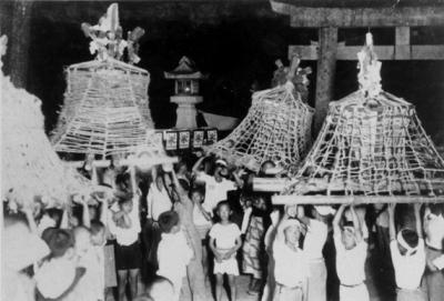 たくさんの子供達が、木で作られた4挺の灯籠を両手高く持ち上げている灯籠祭りの白黒写真