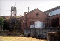 レンガ造りの旧汽かん室の建物と傍に設置された大きなタンクの写真