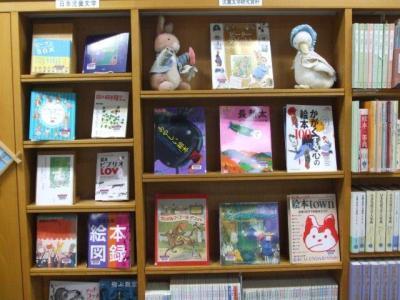 児童文学研究書コーナーの本棚に面展示されている本と、ウサギとアヒルの置物の写真