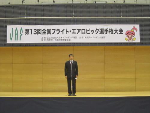 第13回全国フライト・エアロビック選手権大会と書かれた幕がかけられた舞台上で挨拶をする町長の写真