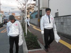 袋を片手に道路の清掃活動を行っている町長と参加者の人の写真