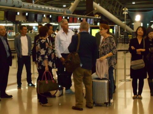 空港内で町長とスーツケースやカバンを持った外国人の方達が集まって立ち話をしている写真