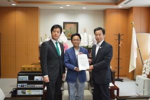 胡蝶蘭の置かれた部屋に左から丸山ほだか衆議院議員、丹羽秀樹文部科学副大臣、町長が並んでいる記念写真