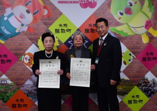 表彰状を持ち立つ女性2人と、その横に立つ町長の写真