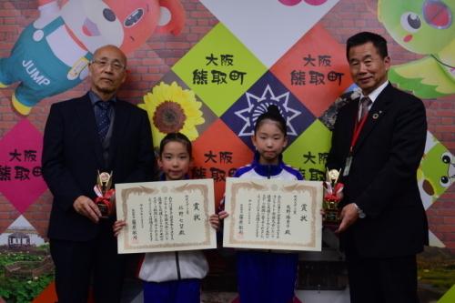 スポーツ賞を受賞した矢野 陽奈子さんと北野 七望さんが笑顔で表彰状を持ちその両脇に立つ町長と男性関係者の写真