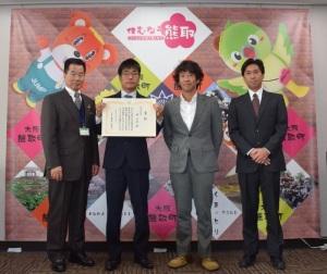 4名のスーツ姿の男性のうち左から2番目の方が賞状を持って写した記念の集合写真