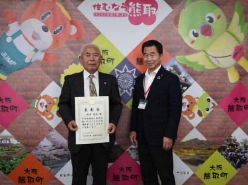 表彰状を持った坂田英信さんと町長が並んで立っている記念写真