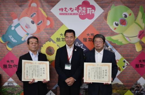 中央に町長が立ち、その左側に榎本宗弘さん、右側に福田芳則さんがそれぞれ感謝状を持って並んで立っている記念写真