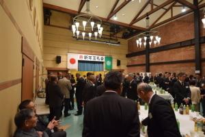 寿新年互礼会と書かれた会場で大勢の参加者達がそれぞれ談笑をしている様子を写した写真