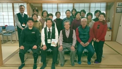 奥に障子がある畳の部屋で参加者達と町長が集まって並んでいる集合写真