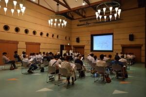 煉瓦館で、タウンミーティング参加者が、前方のスクリーンを注目している写真