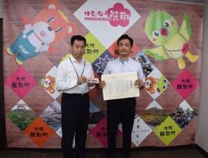 賞状を持つ下中自動車株式会社 安藝 幸司 様と、その横に立つステッカーを持った町長の写真