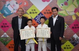 柔道着を着て賞状を持つ男の子2名とその横に立つ、町長と男性の記念写真