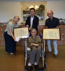 車いすで座られている方の後ろに立つ町長と、両側にいる方々が額縁をこちらに向けている写真