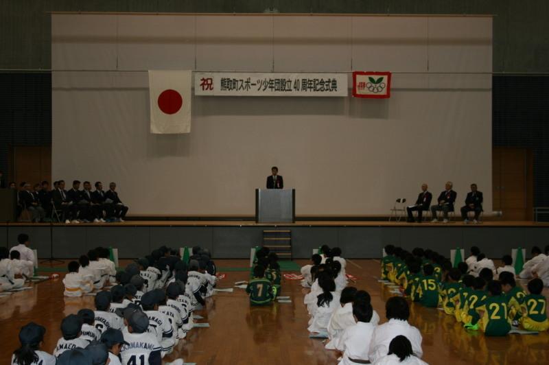 体育館の床には沢山のスポーツ少年団の子供たちが並んで座っていて、舞台の上で町長が話をしている記念式典の写真