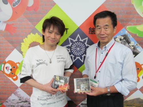 CDを持ち微笑んでいるアニメシンガーの喜多修平さんと町長の写真